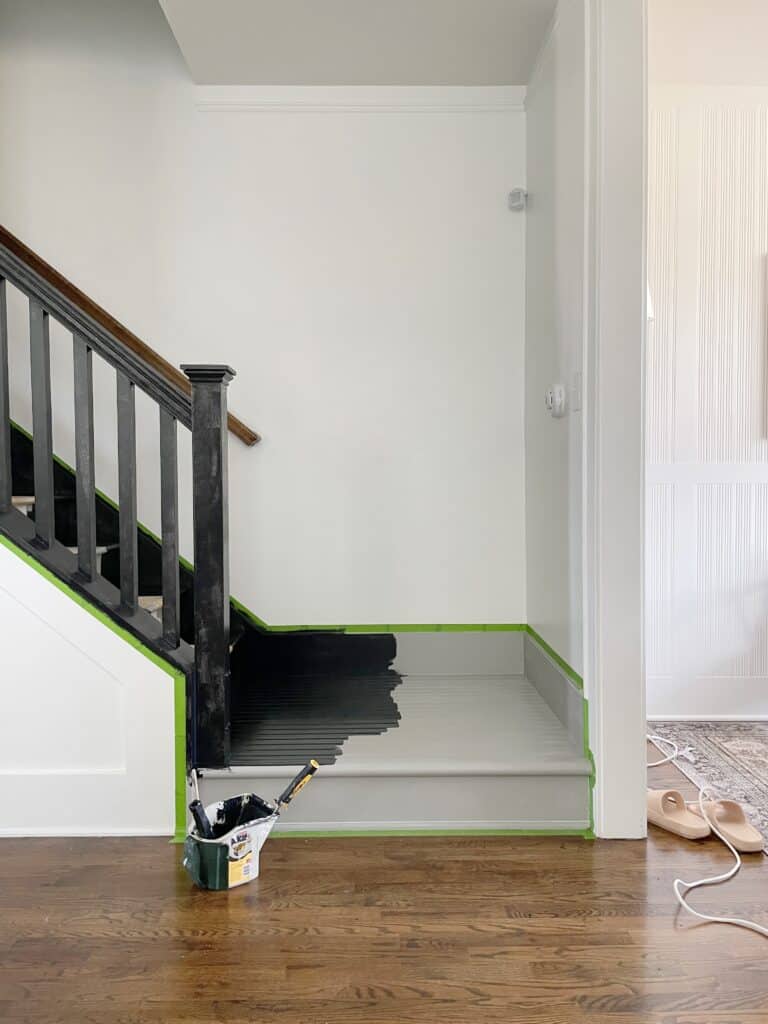 Stair landing in the midst of being painted black for a DIY staircase makeover