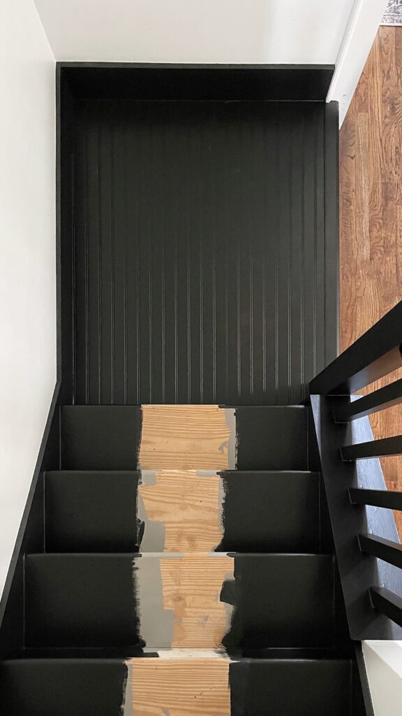 Freshly painted black stairs with a beadboard landing