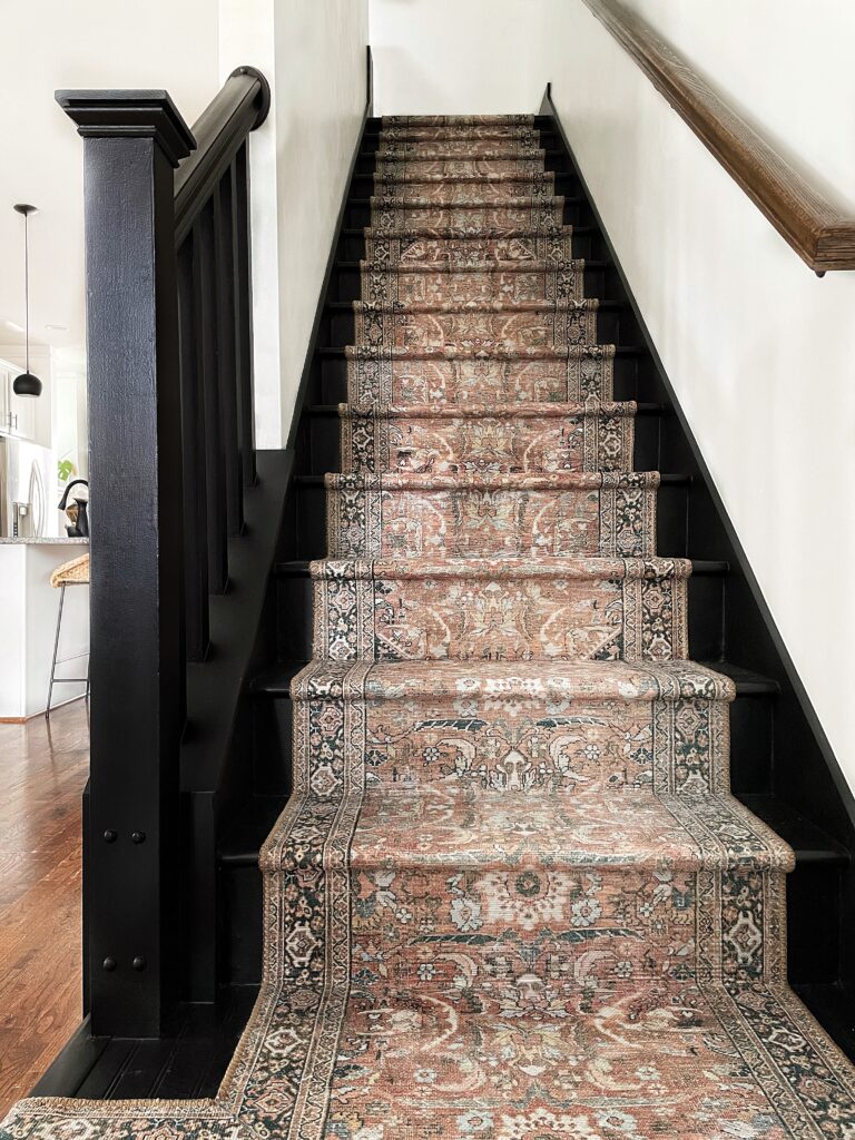 Completed DIY stair runner. Black stairs with terracotta printed vintage runner down the middle