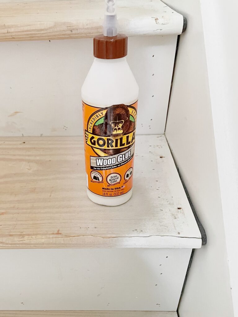 Gorilla wood glue sitting on the top of a cracked stair tread after a DIY stair Reno
