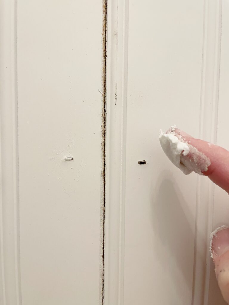 Elisha from Our Aesthetic Abode is filling small nail holes with a lightweight sparkle for her beadboard entryway makeover
