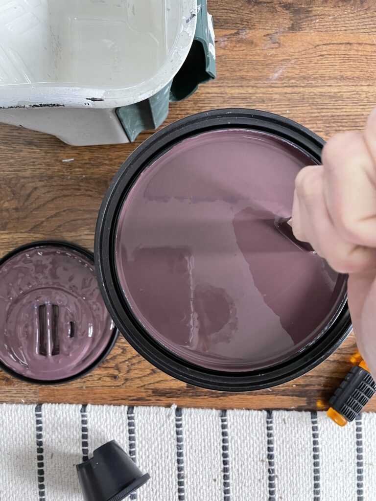 Elisha from Our Aesthetic Abode is stirring purple paint for her beadboard entryway makeover