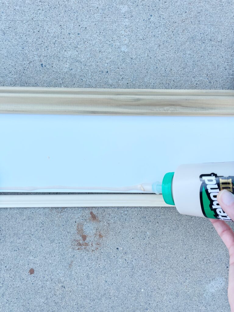 Elisha from Our Aesthetic Abode is using wood glue to attach the two pieces of trim to MDF for her beadboard entryway makeover