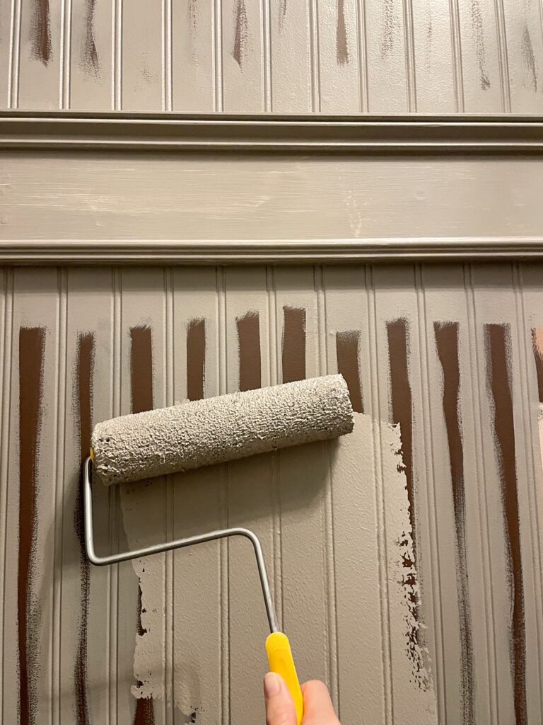 Elisha from Our Aesthetic Abode is using a roller brush and painting over the beadboard for her beadboard entryway makeover