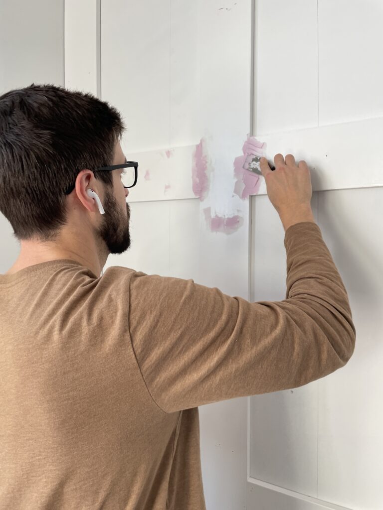 Dan from Our Aesthetic Abode is using spackle to fill all the seams and nail holes in the MDF for the DIY recessed wainscoting accent wall