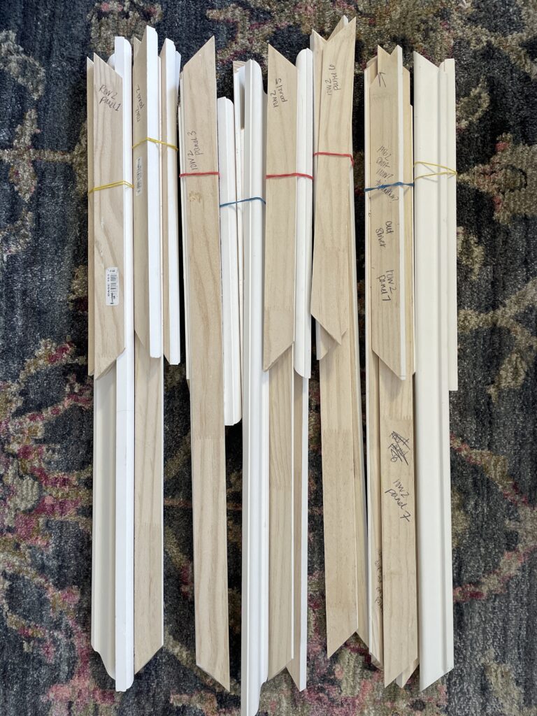 Elisha from Our Aesthetic Abode is showing how she organized her trim pieces for her Recessed Wainscoting Accent Wall. She dry fit the pieces, labeling which panel they belong to, and bundled them up with rubber bands.