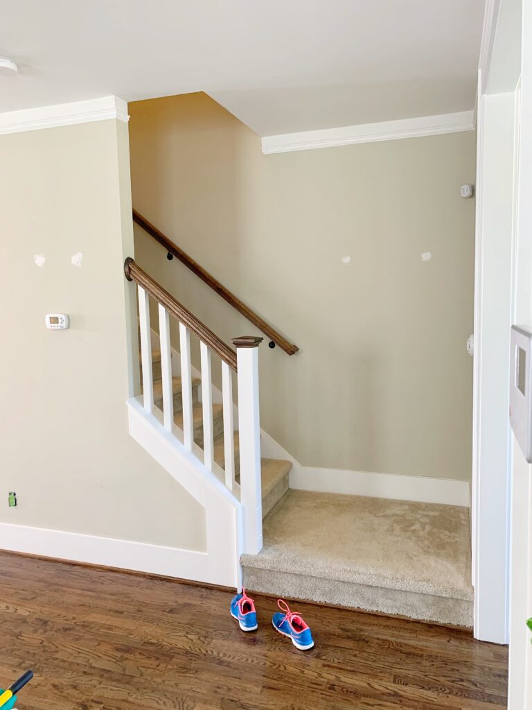 Green walls, beige carpeted stairs with a white and wood stair railing
