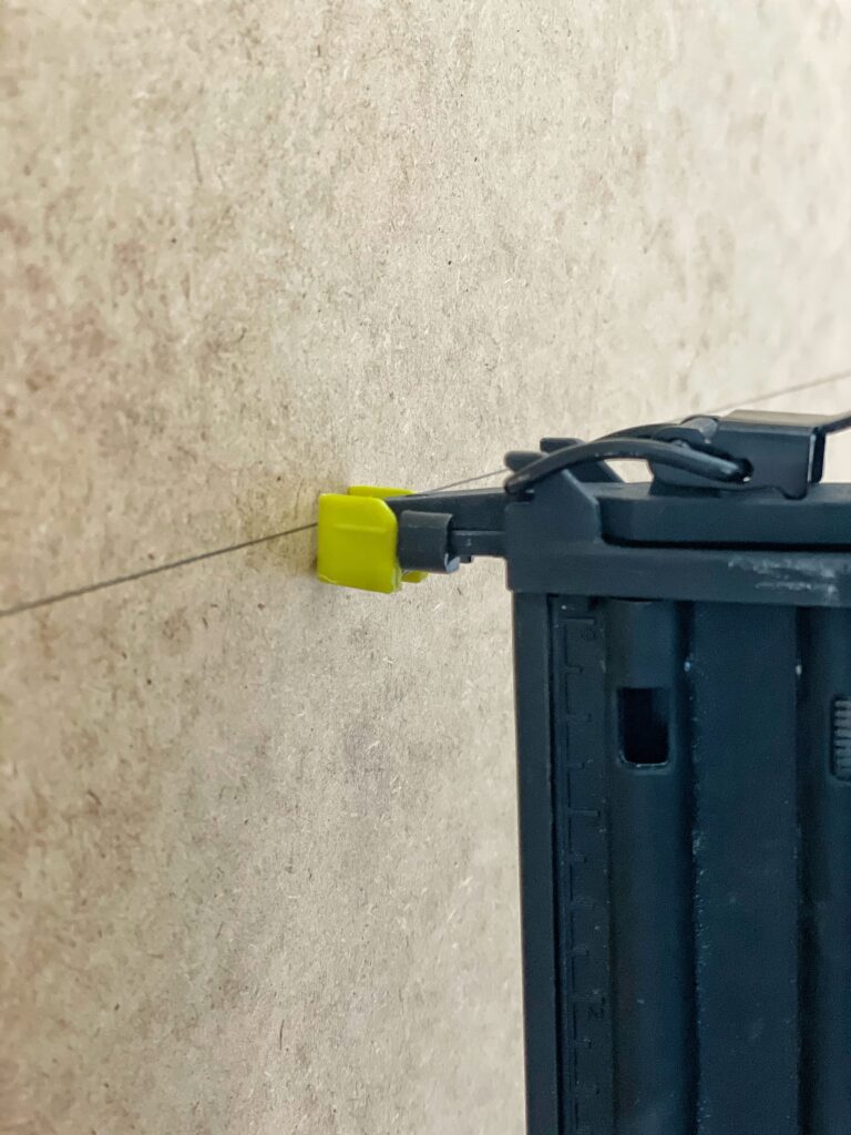 A close up view of a nail gun lined up to nail the backing of an Ikea bookcase into the shelves