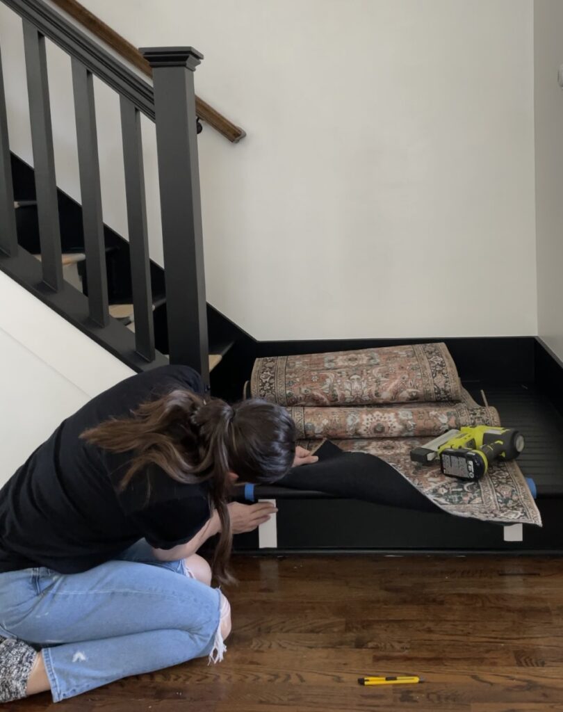 Elisha from Our Aesthetic Abode is adding carpet tape along the riser for her stair remodel