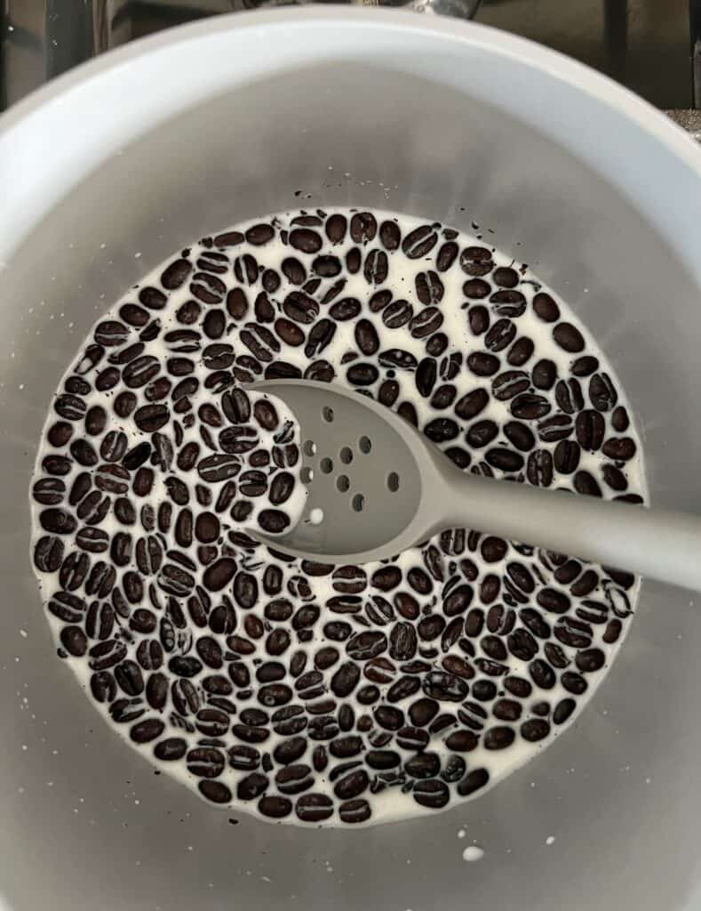 dark coffee beans and milk in a saucepan for homemade coffee ice cream