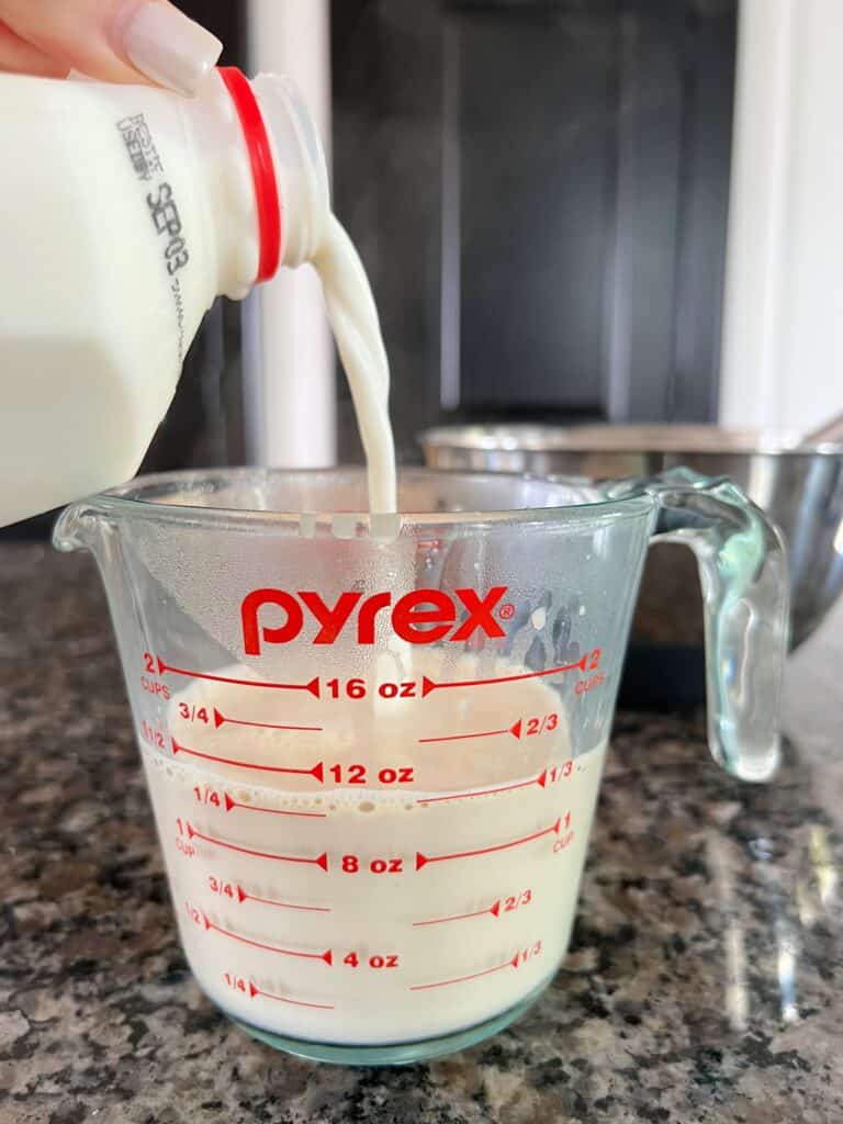 milk is being added to a liquid measuring cup for homemade coffee ice cream