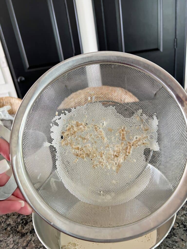 A strainer with junk on it after straining a homemade coffee custard