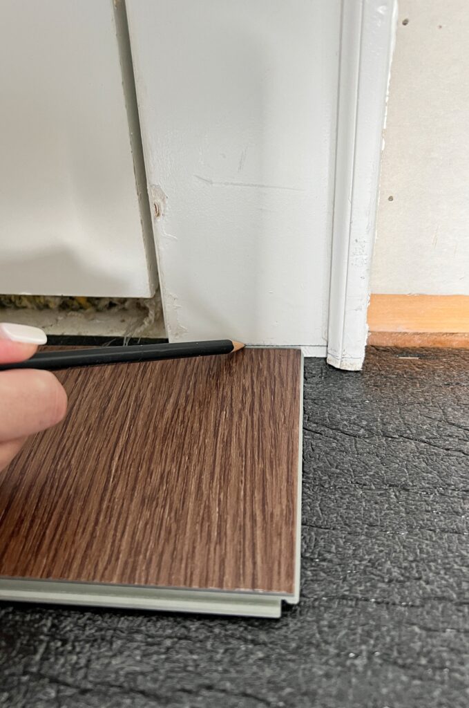 Marking the thickness of LVP flooring to cut into a door frame