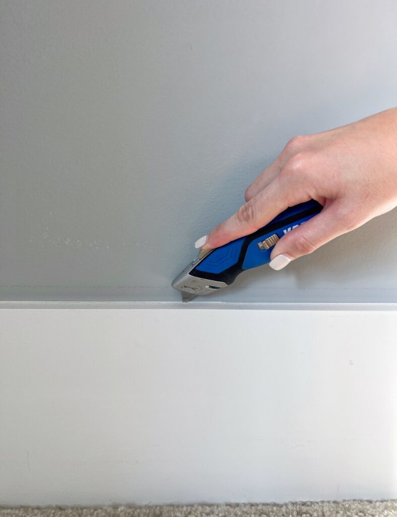 Using a utility knife to score the caulk before removing baseboards