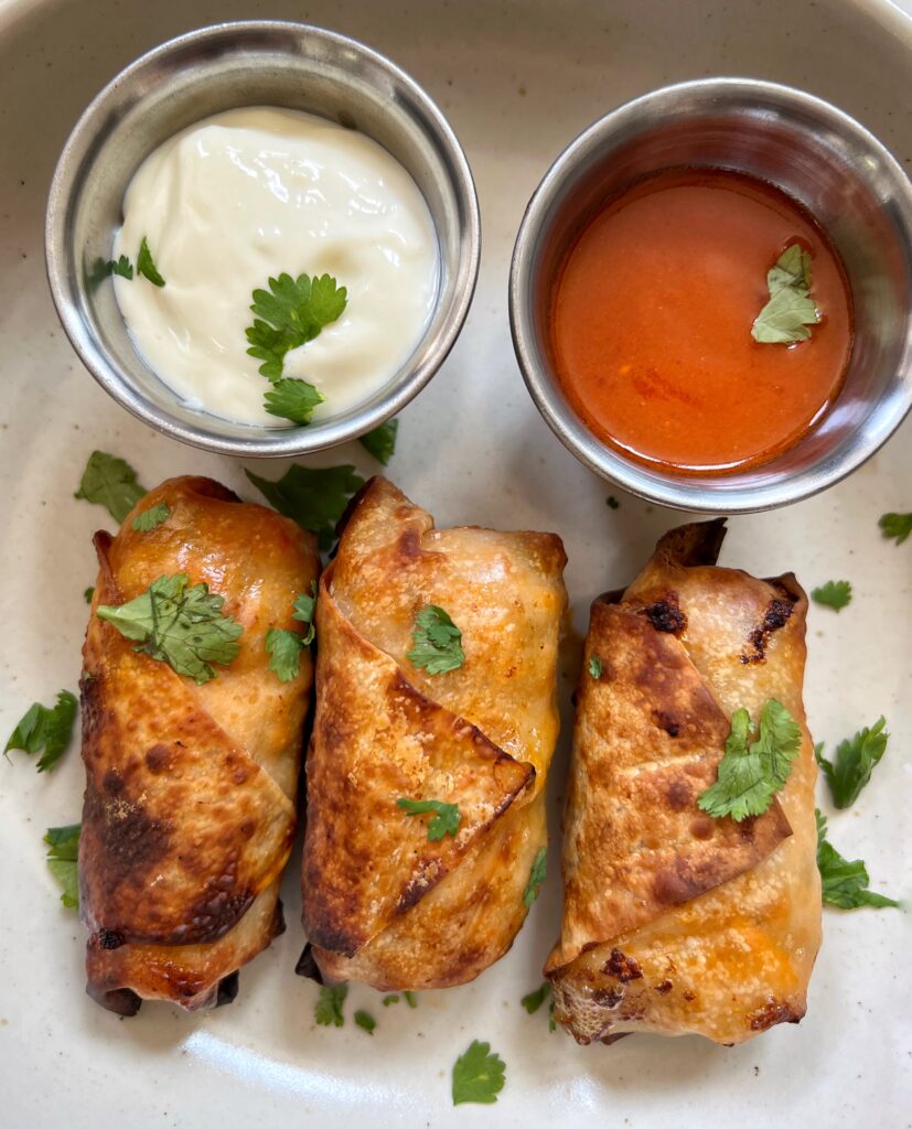 3 homemade air fryer buffalo chicken egg rolls with a side of buffalo sauce and blue cheese dressing