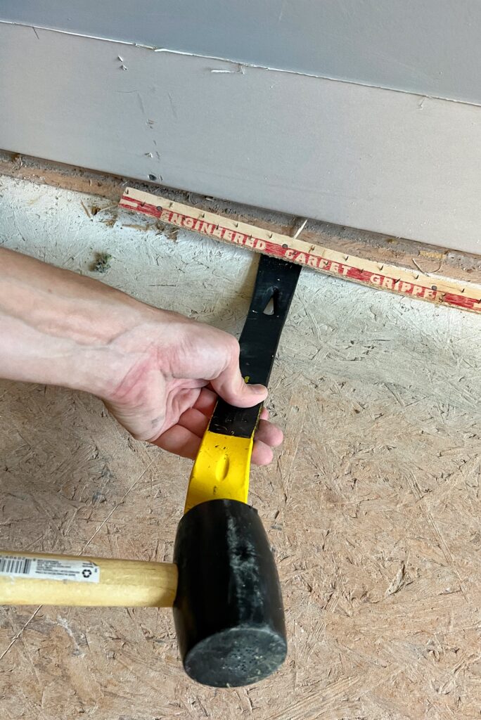using a pry bar to lift up a tack strip before installing lvp