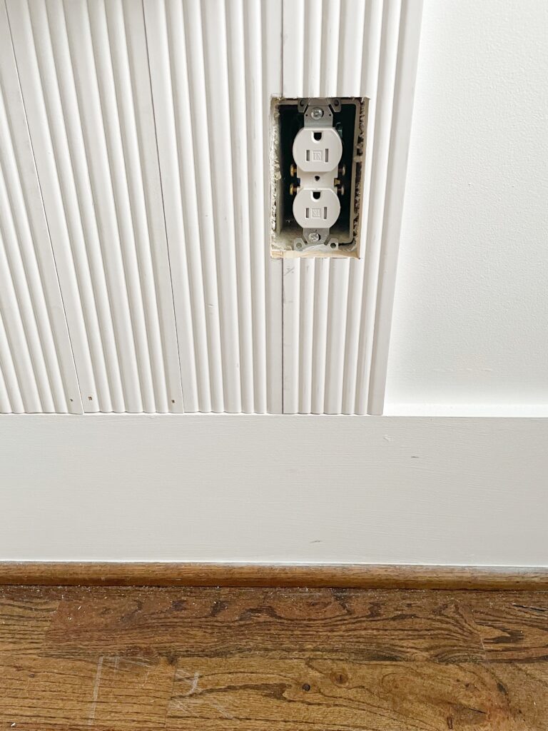 Fluted wood panels cut around an outlet for an accent wall