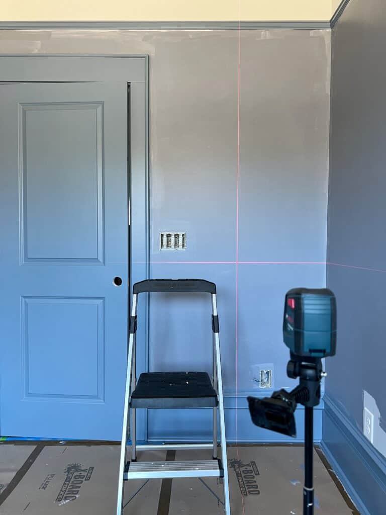 Hanging the first wallpaper panel against the door frame and with a laser level