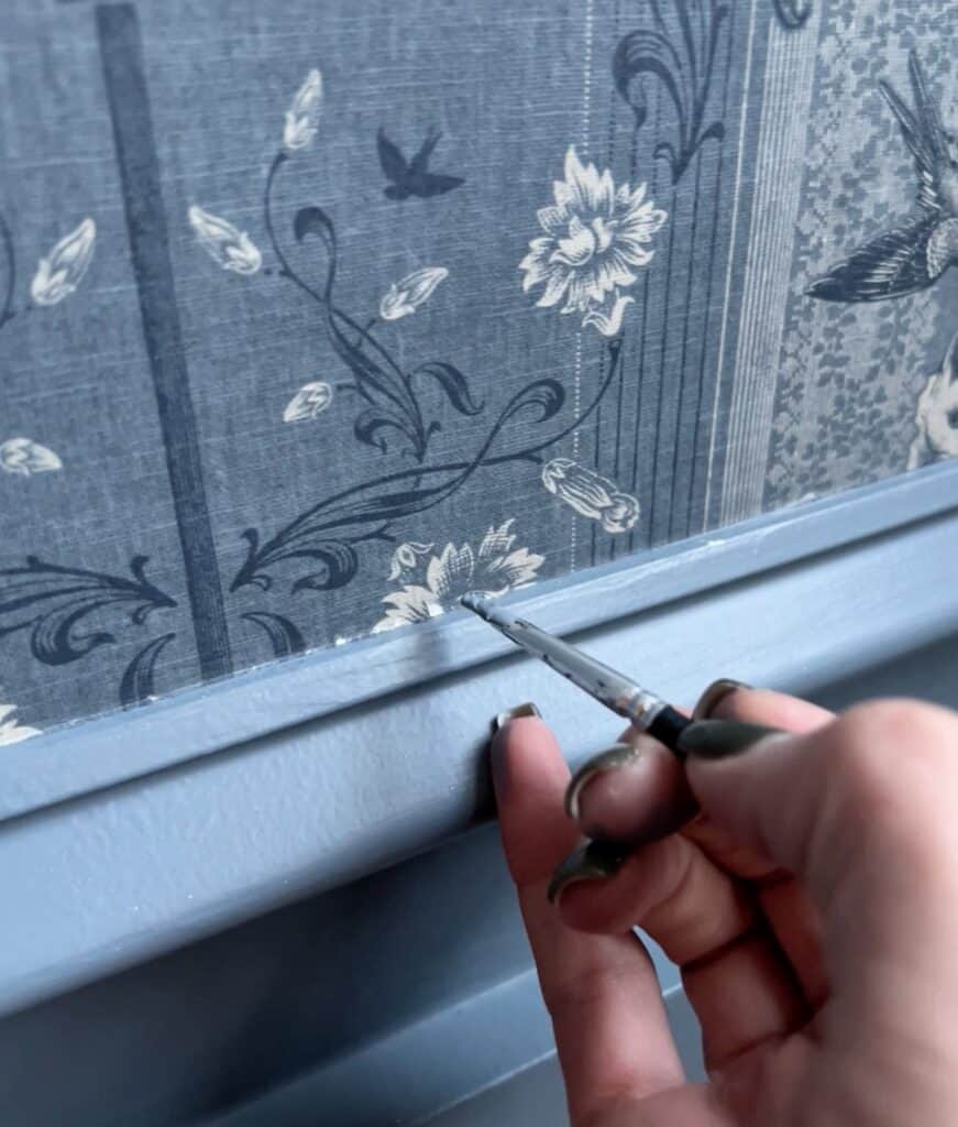 using a small brush to touch up a tear in wallpaper