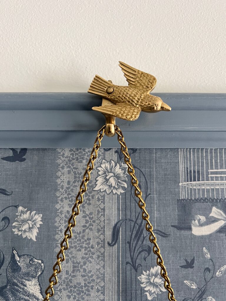 brass bird picture hook that is swung open to the side