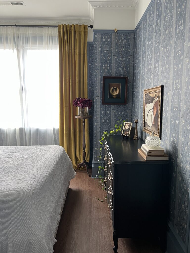 blue floral wallpapered bedroom with a black french dresser
