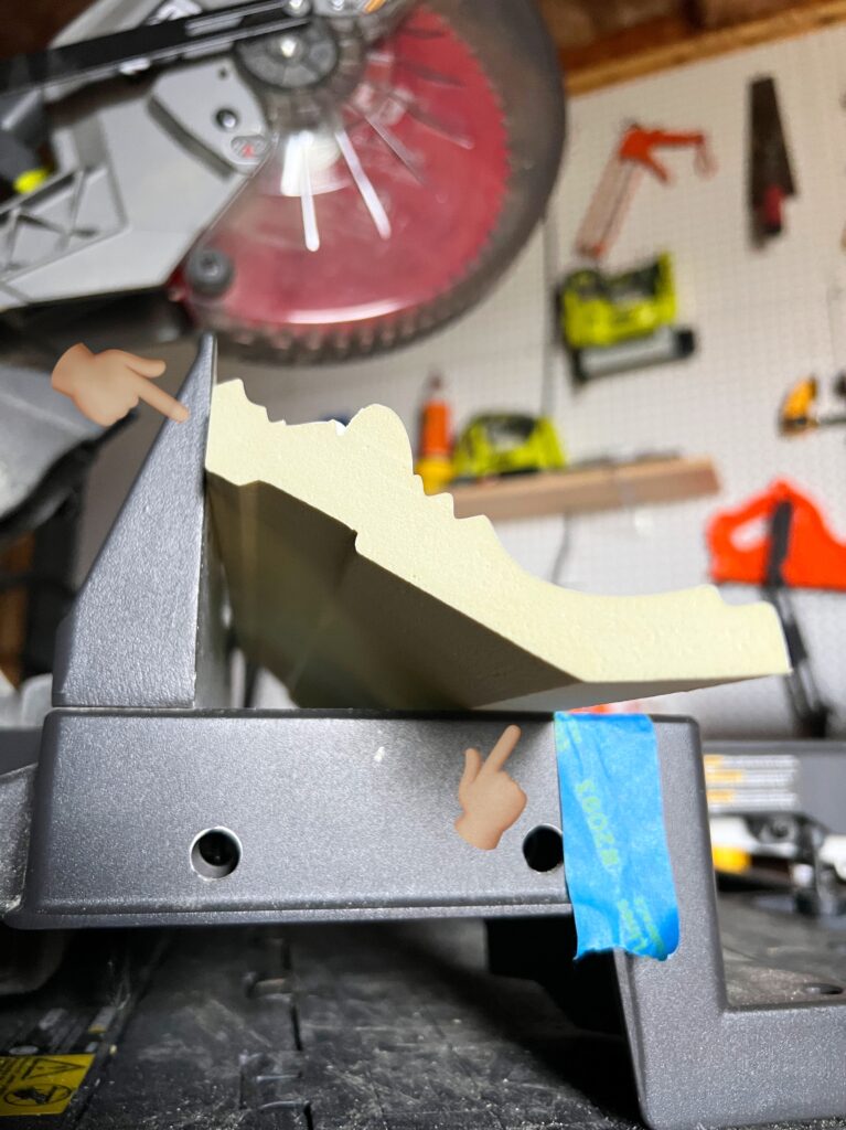 crown moulding resting on a miter saw with the back against the fence