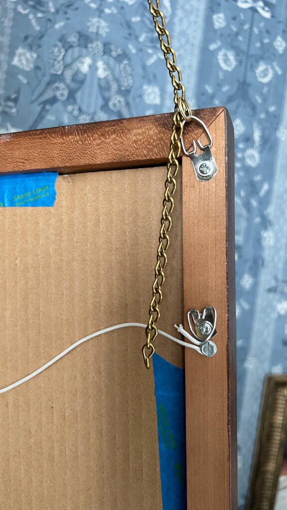 The back of a frame with a D-ring screwed in and chain attached with keychain ring