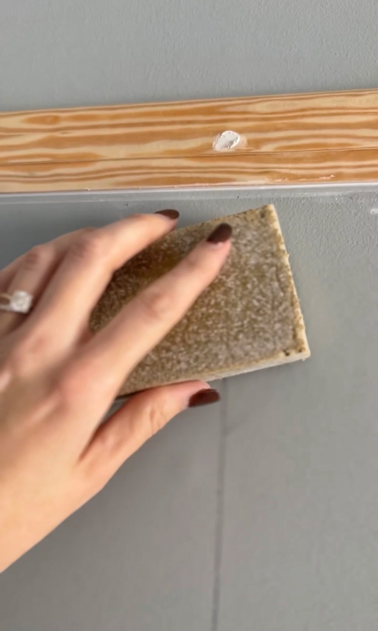 Using a sanding sponge to sand down spackle on picture moulding