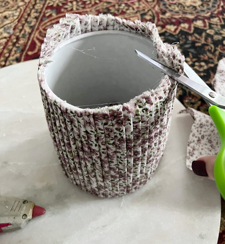 trimming the excess fabric off of a DIY pleated lampshade