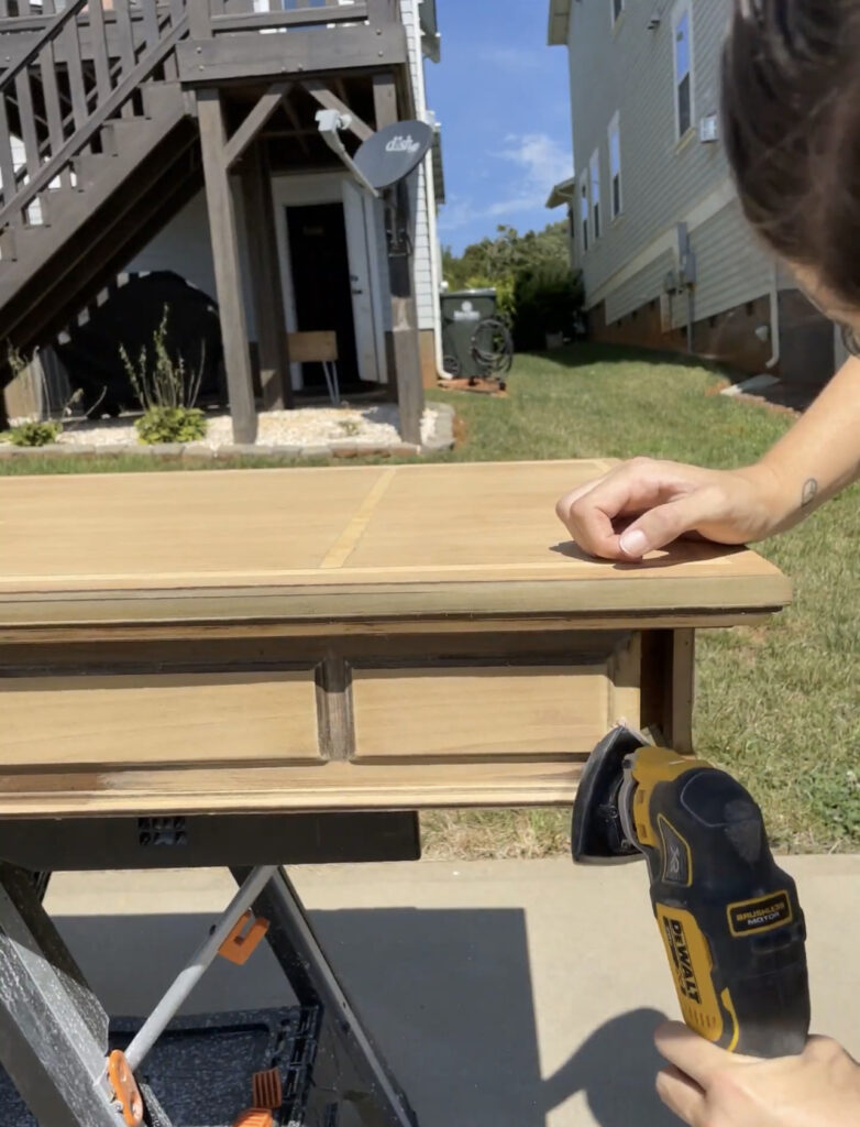 Using a multi-tool sanding attachment to get into small areas on a desk