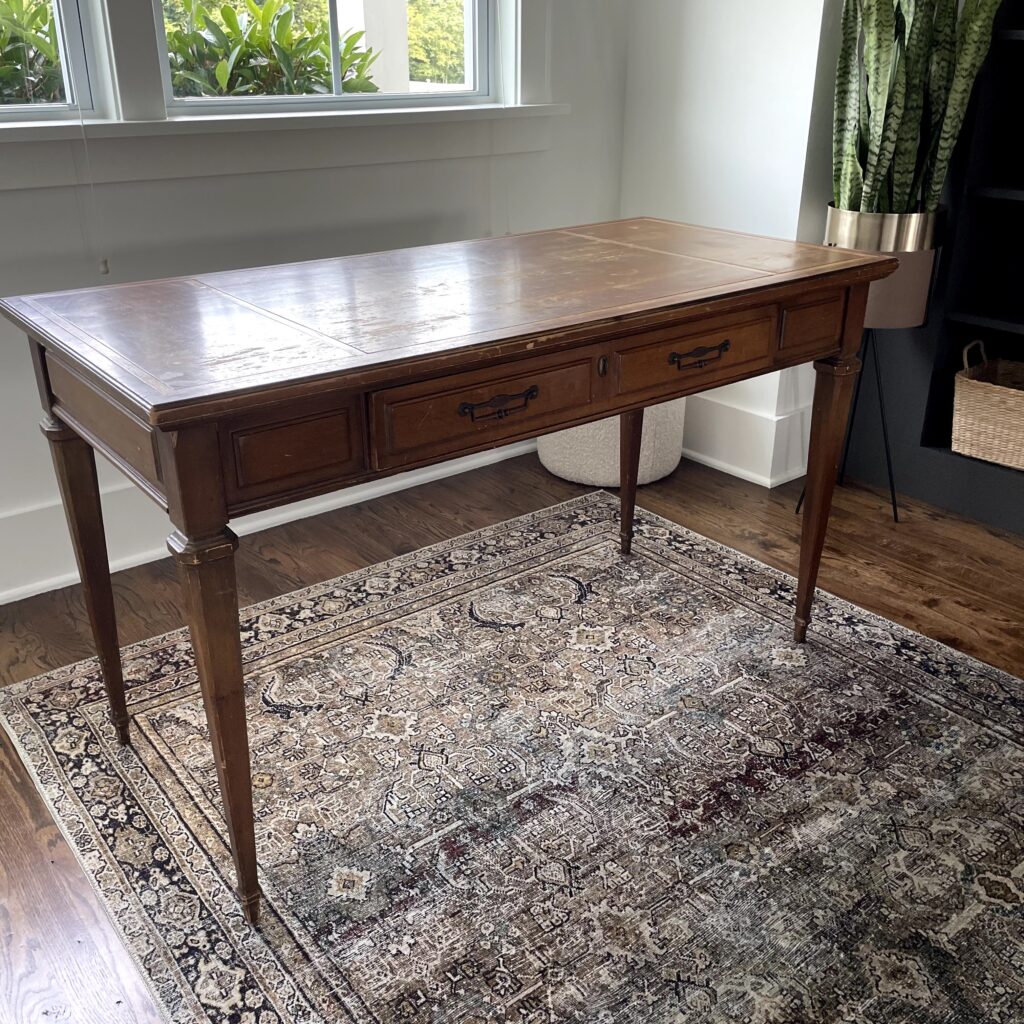 a before photo of a federal style vintage writing desk with some imperfections on the top