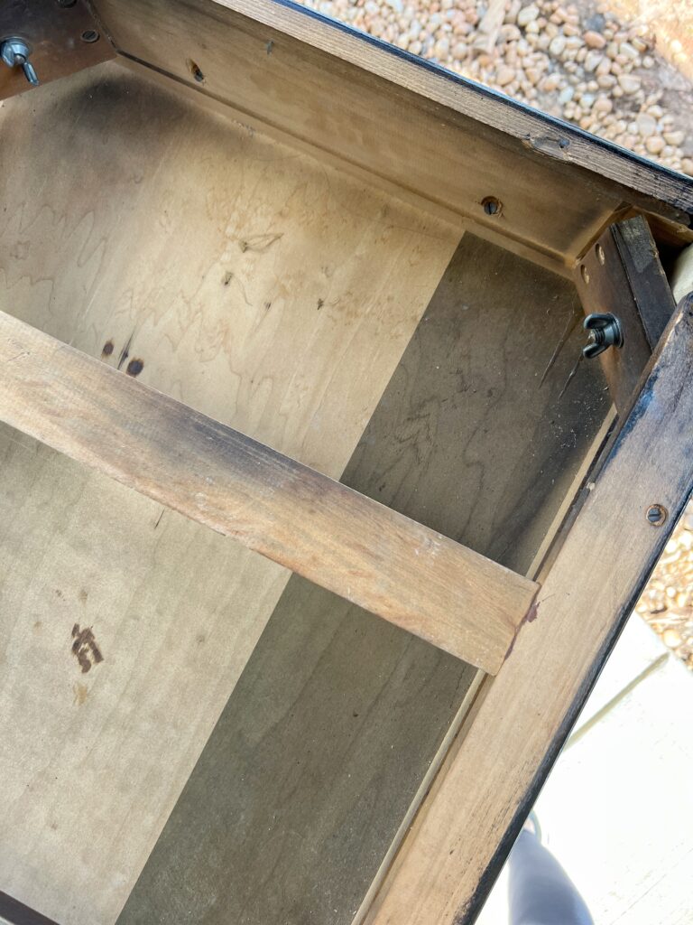 the underside of a vintage desk which has what looks like 2 different types of wood used for construction