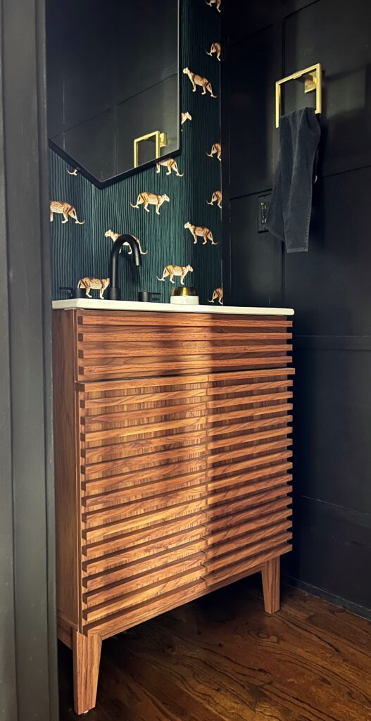 black bathroom with leopard wallpaper and a wood slat vanity