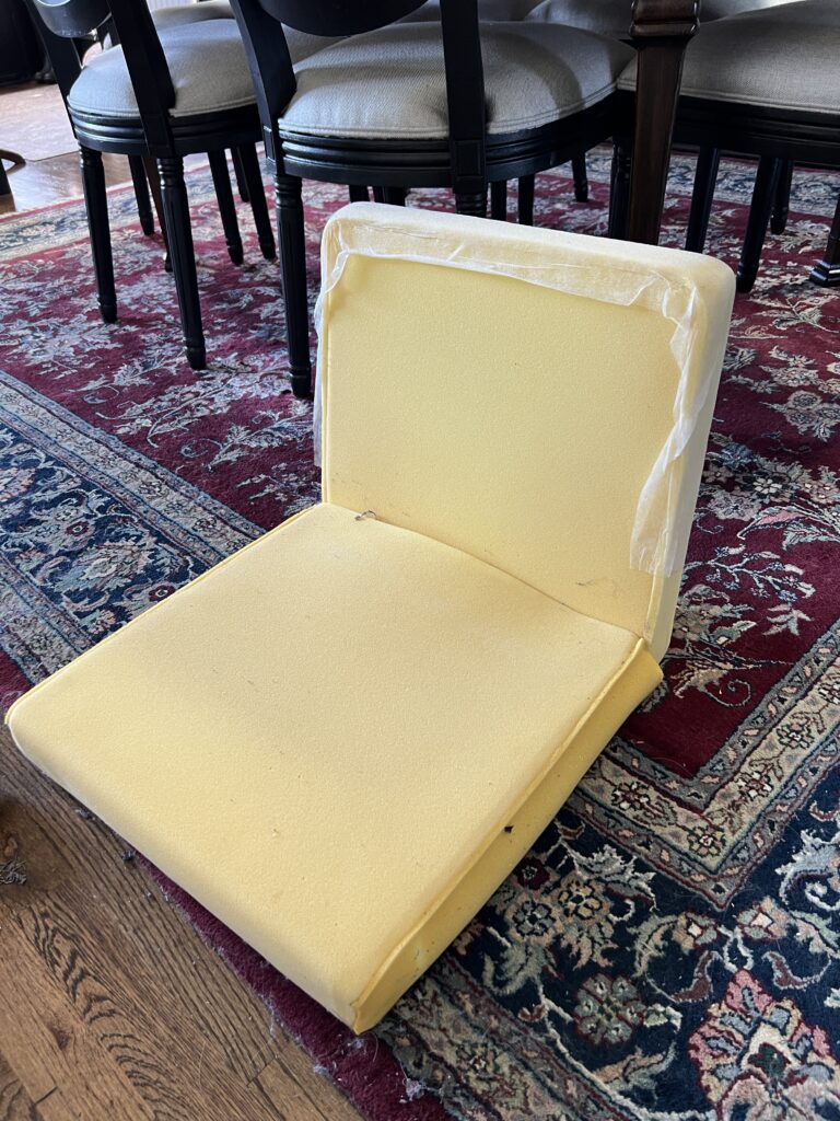 A chair seat and back with the upholstery removed and the foam padding exposed