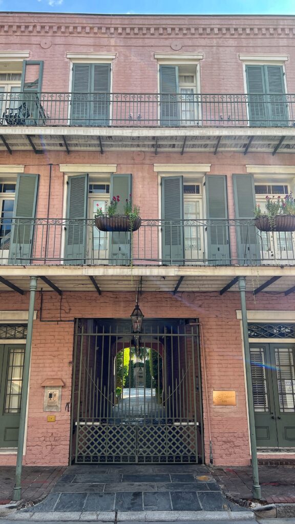 pink brick home with green shutters in the french quarter