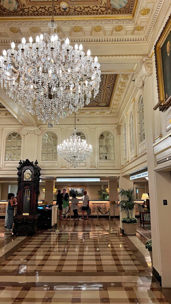a hotel lobby with ornate moulding, marble checkered floor, and large chandeliers