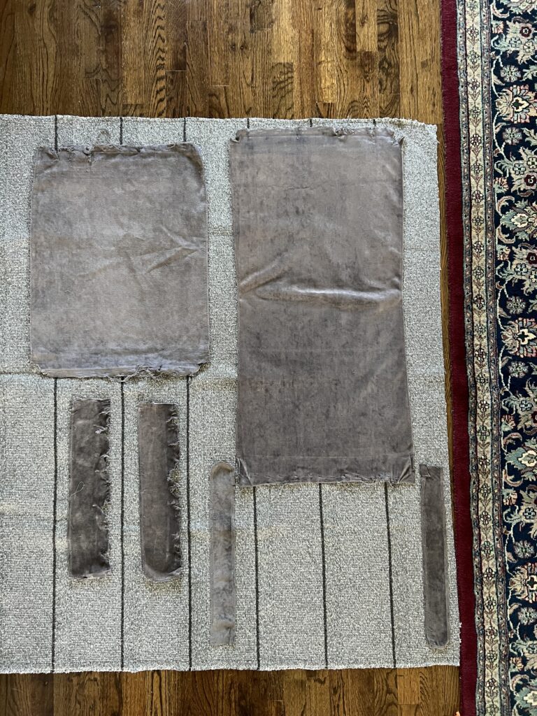 old chair upholstery pieces laid on top of new fabric for reupholstering a chair