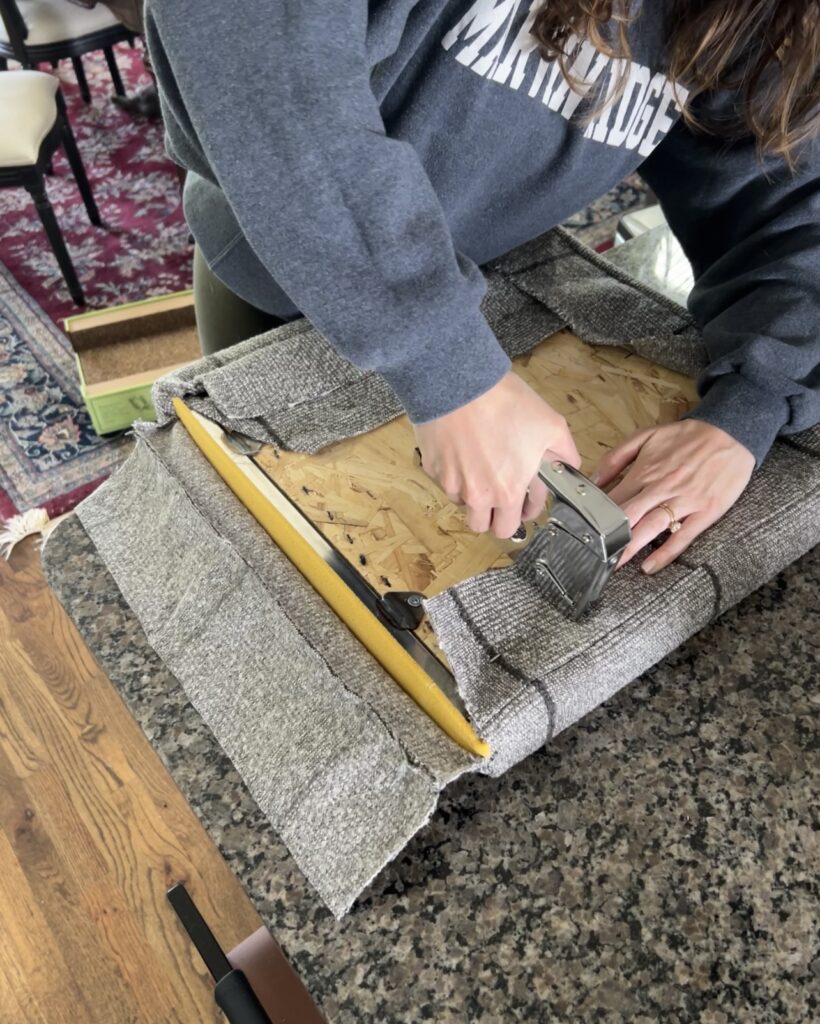 stapling new upholstery to the bottom of a chair