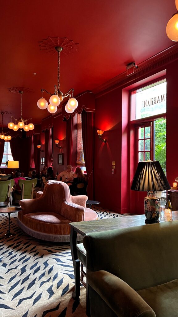 a speakeasy style bar with red walls and ceilings and a tiger print carpet