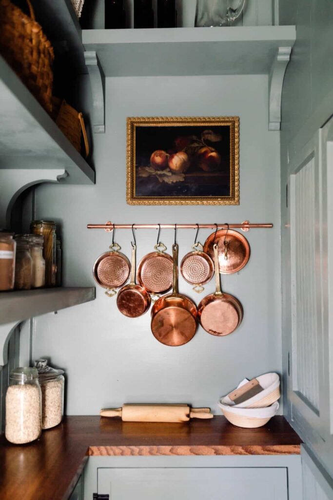 Blue walk in pantry with vintage copper pots on a rail